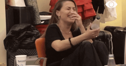 a woman is laughing while holding a bottle and a cup that says ' beco ' on it