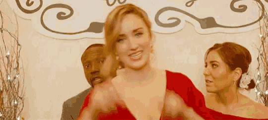 a woman in a red dress is standing next to a man and two other women .
