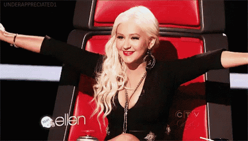 a woman with blonde hair is sitting in a red chair with her arms outstretched and the words ellen on the bottom
