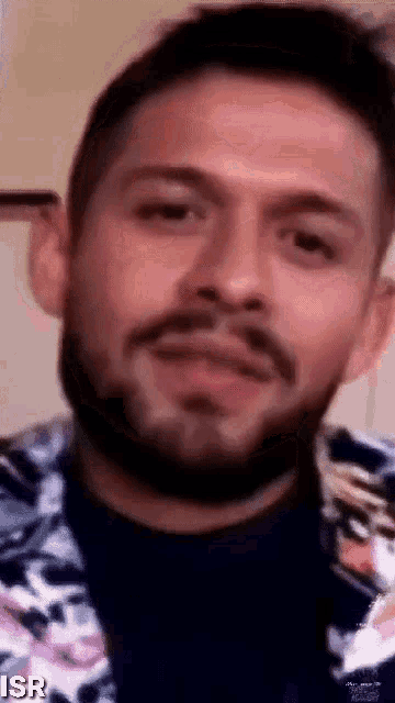 a close up of a man with a beard wearing a floral jacket .