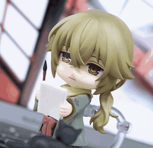 a figurine of a girl holding a brush and a book