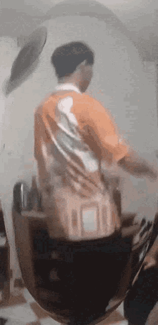 a man in an orange shirt is standing in front of a mirror ..