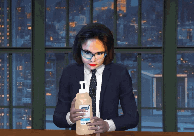 a woman in a suit and tie holds a bottle of lysol hand sanitizer