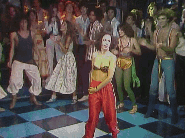 a woman in red pants is dancing on a checkered floor