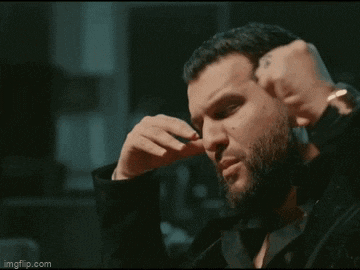 a man with a beard is sitting at a table with his mouth open .