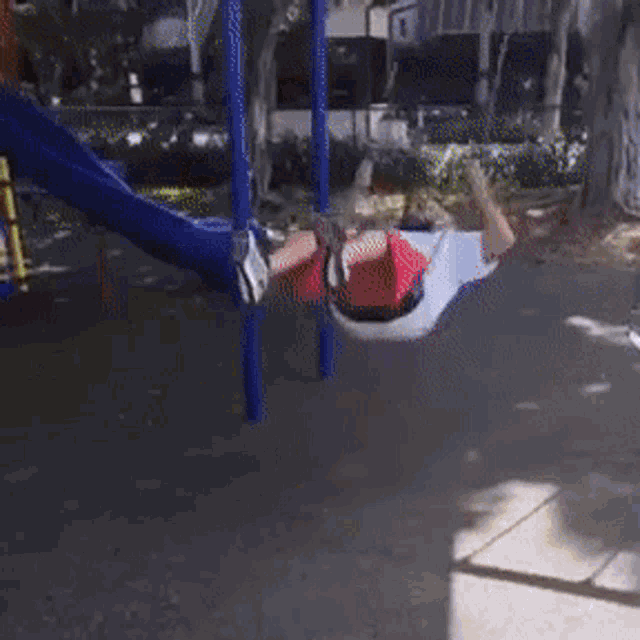 a man in red shorts is swinging on a swing set