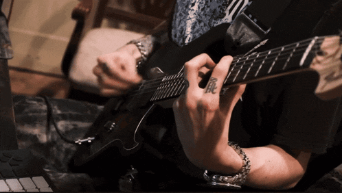 a person is playing a guitar with a tattoo on their finger