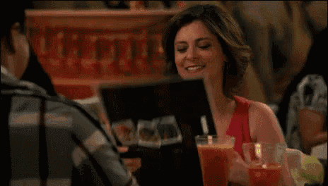 a woman sitting at a table talking to a man with the words " we 'll see about that " at the bottom of the screen