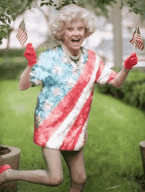 an elderly woman wearing an american flag shirt and red gloves is running and holding two american flags