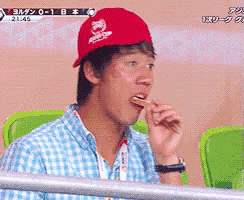 a man wearing a red hat with a dragon on it is eating something