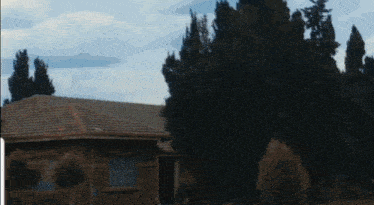 a house with a tiled roof is surrounded by trees and bushes