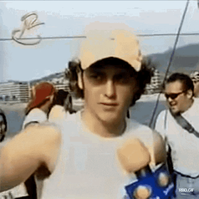 a man wearing a hat is holding a microphone in front of a crowd .