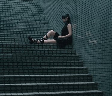 a woman sits on a set of stairs against a tiled wall
