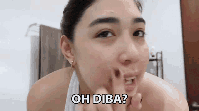 a woman with a towel around her neck is looking at her face and says oh diba ?
