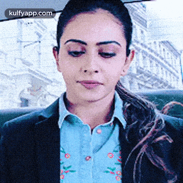 a woman in a blue shirt and black jacket is sitting in a car with her eyes closed .