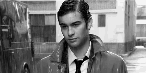a young man in a suit and tie is standing in the rain .