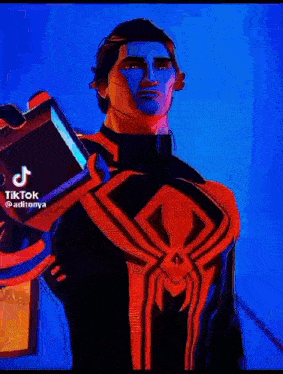 a man in a red and black spiderman suit is holding a book .
