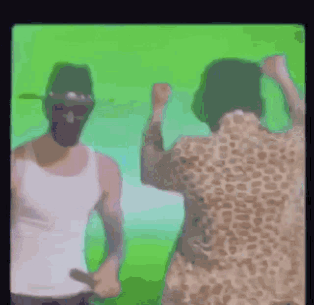 a man in a white tank top is standing next to a woman in a leopard print shirt .