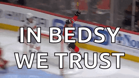 a hockey player celebrates a goal with the words in bedsy we trust below him