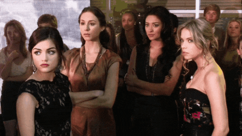 a group of women are standing with their arms crossed in a room