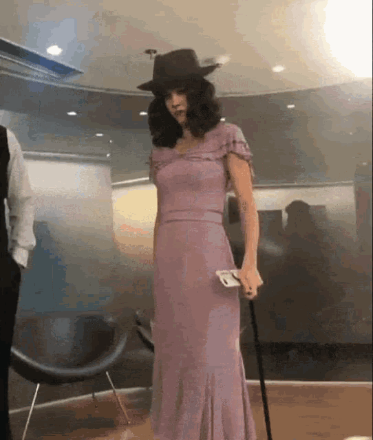 a woman in a purple dress is holding a cane and a cell phone