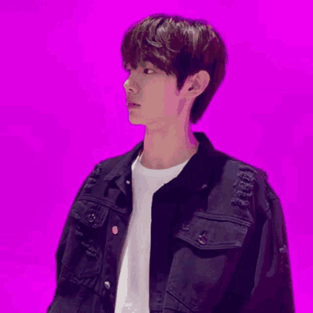 a young man is wearing a black denim jacket and a white shirt .