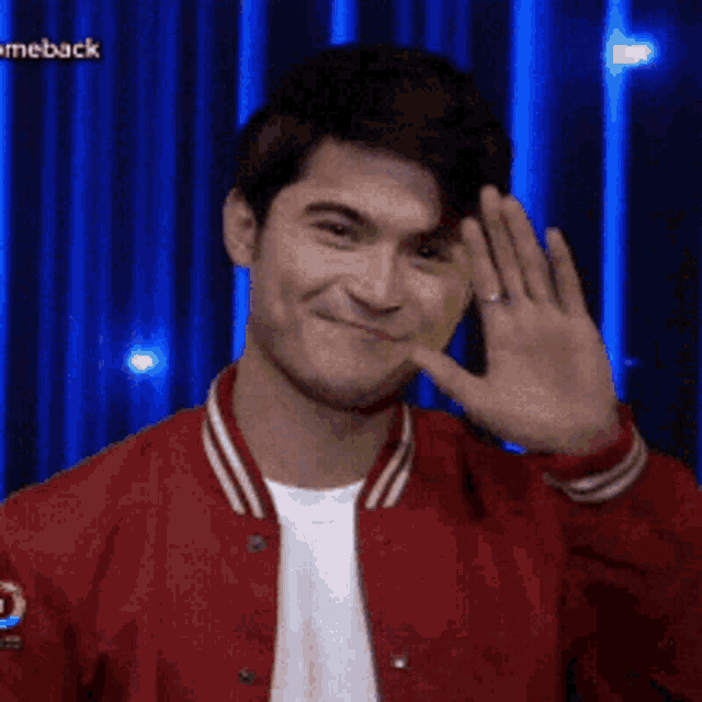 a man in a red jacket is smiling and waving