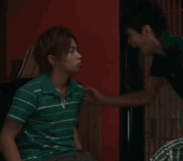 a man in a green striped shirt is laughing with another man in a blue shirt