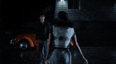a man and a woman are kissing in front of a car