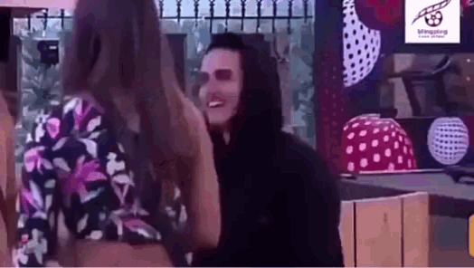 a man in a hoodie is talking to a woman in a floral top