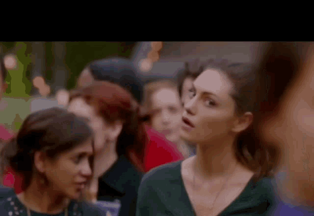 a woman is standing in a crowd of people looking at something .