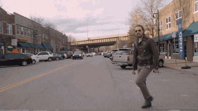 a man is walking down a street with a sign that says open