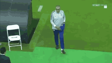 a man walking on a soccer field with a chair in the background
