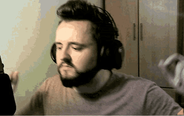 a man with a beard is wearing headphones and a gray shirt