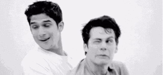 a couple of men are standing next to each other and one of them is making a funny face .