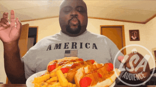 a man wearing an america shirt is eating a hot dog