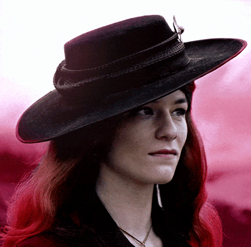 a woman wearing a black hat with a feather on it