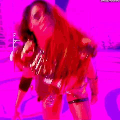 a woman with red hair is standing in front of a purple background and the words the next thing are visible .