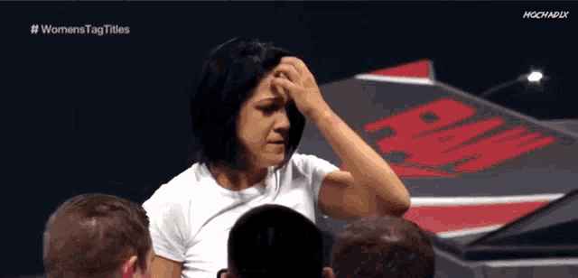 a woman holds her hand to her forehead in front of a screen that says womenstag titles