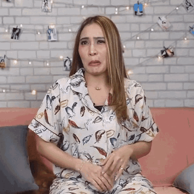 a woman is sitting on a couch with her hands on her stomach and making a face .