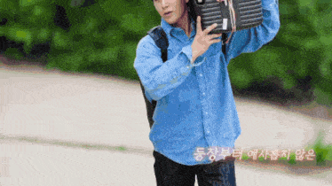 a man in a denim shirt is carrying a suitcase with foreign writing on it