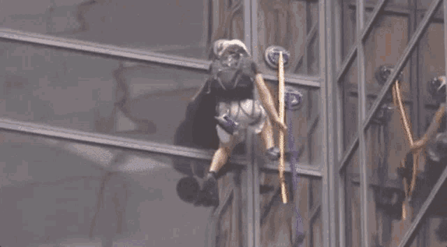 a man is climbing a building with a rope attached to it .