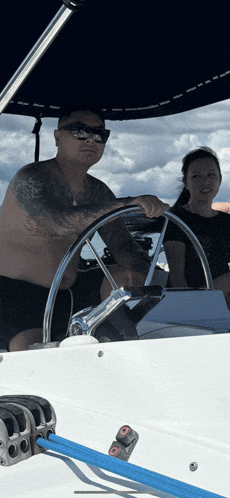 a man and a woman are sitting on a boat and the man is holding the steering wheel