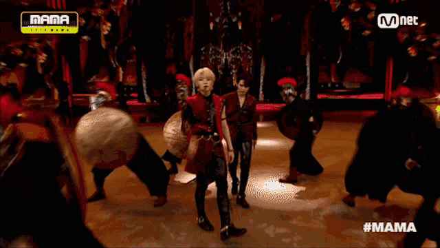 a group of people are dancing on a stage with drums in the background and a yellow sign that says mama on it
