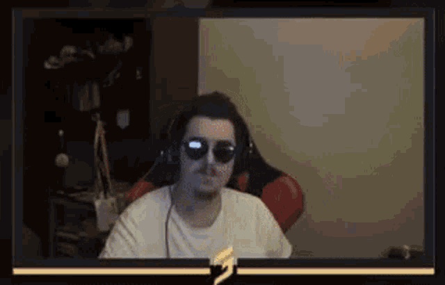 a man wearing sunglasses and headphones is sitting in a chair in front of a computer screen .