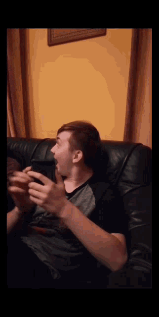 a man is sitting on a couch with his mouth open and his eyes closed
