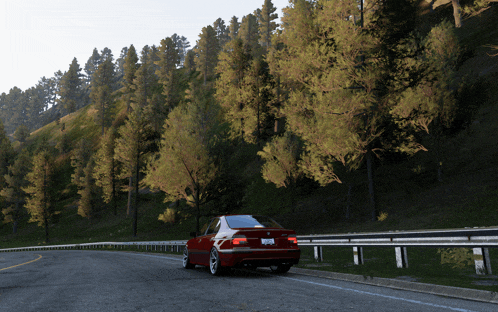 a red car is driving down a road with trees on the side