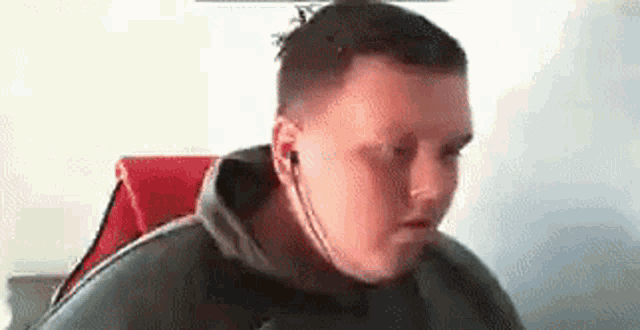 a man wearing headphones is sitting in a chair and looking at the camera .
