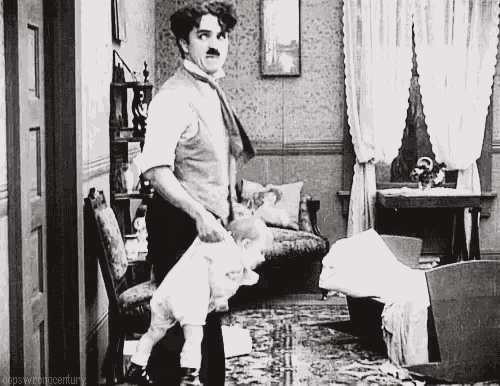 a black and white photo of a man holding a baby in a room .
