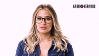 a woman wearing glasses and a blue shirt is scratching her head .